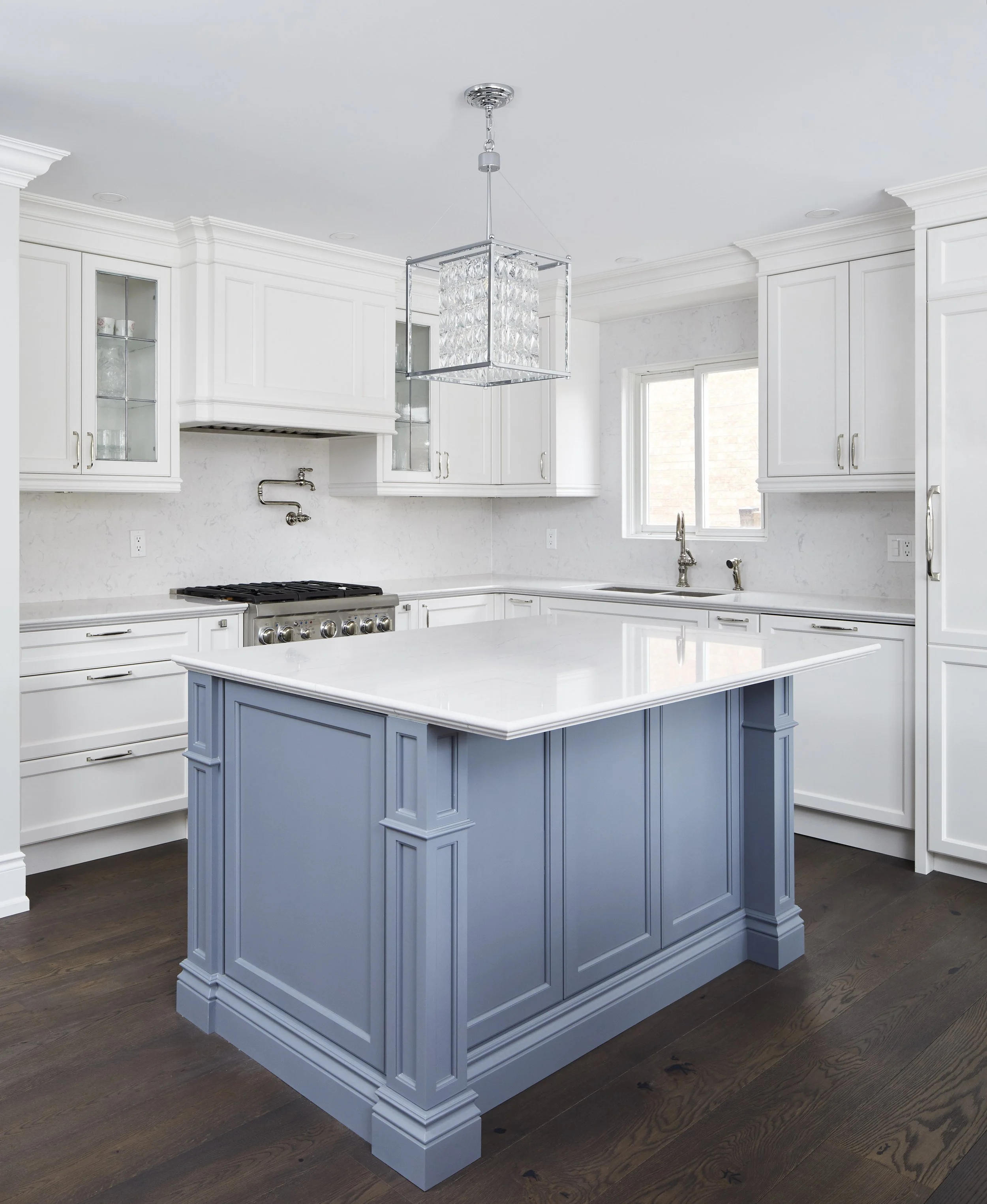 At Seif Designs, we offer top-quality kitchen renovation services around the GTA, Mississauga, Oakville. This traditional kitchen showcases custom white cabinetry with classic detailing and a bold blue island as the focal point. The island features i