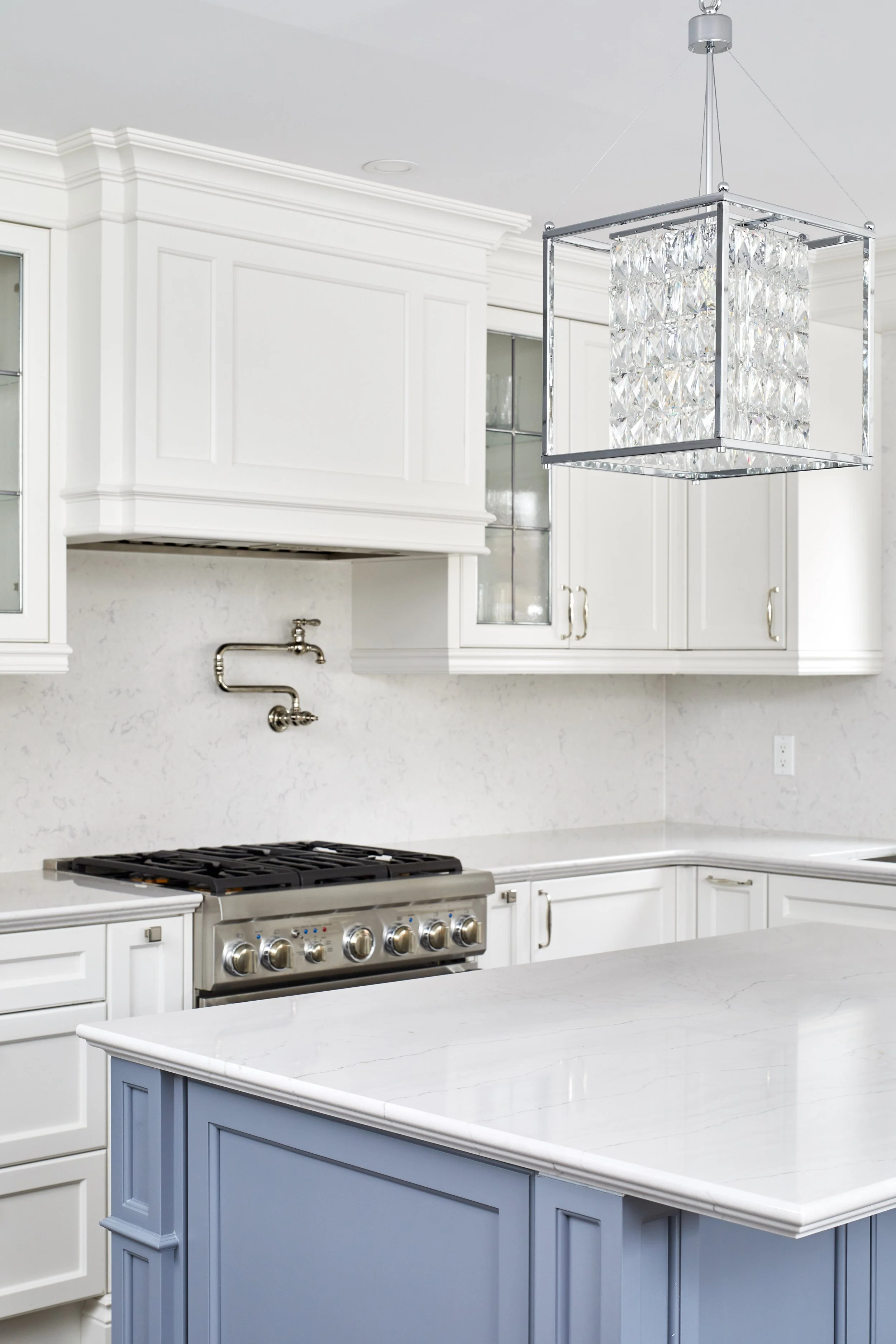 At Seif Designs, we offer top-quality kitchen renovation services around the GTA, Mississauga, Oakville. This traditional kitchen showcases custom white cabinetry with classic detailing and a bold blue island as the focal point. The island features i
