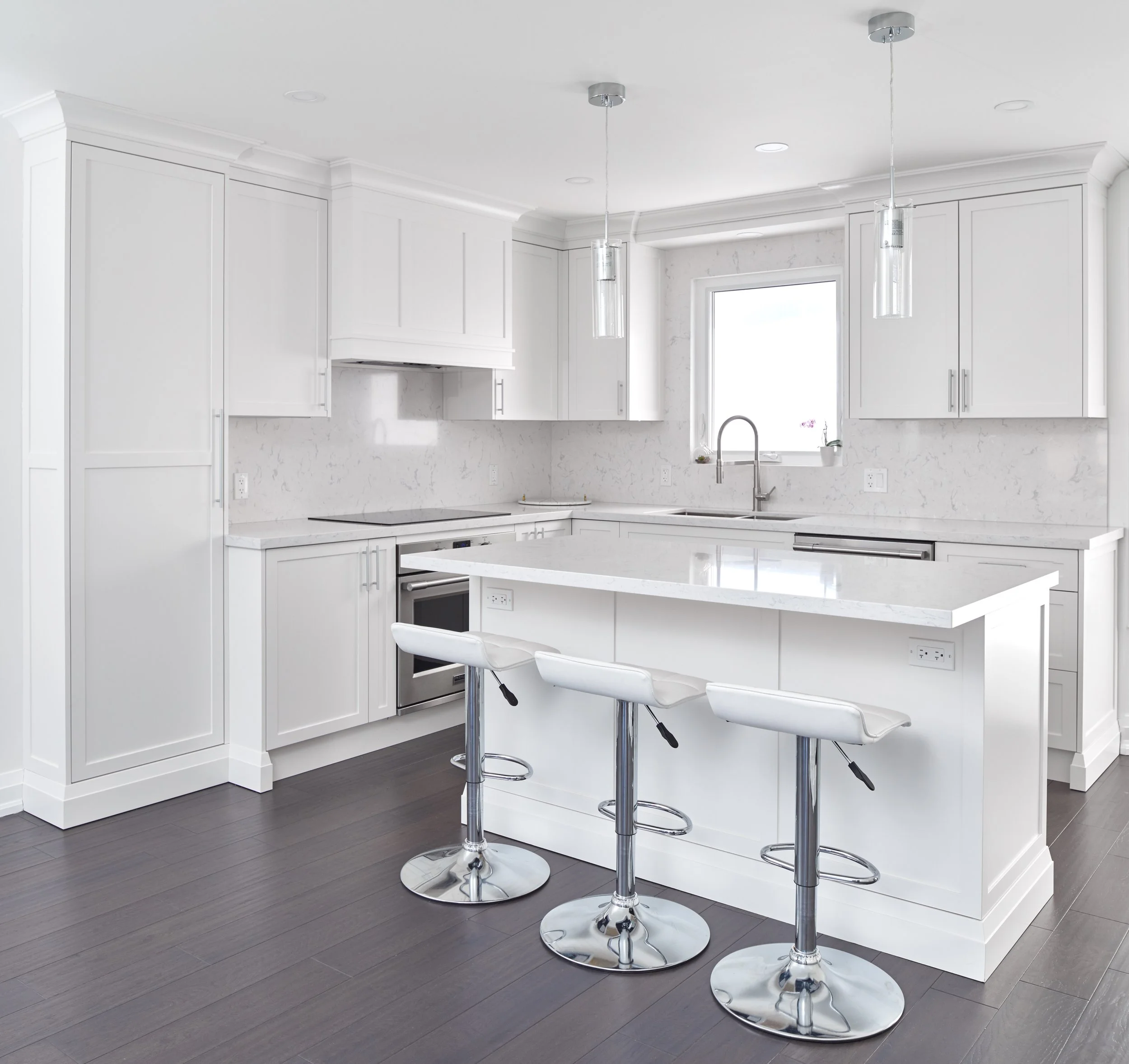 Modern kitchen with white cabinets, marble countertops, a large window, and three white bar stools with chrome bases at the island.