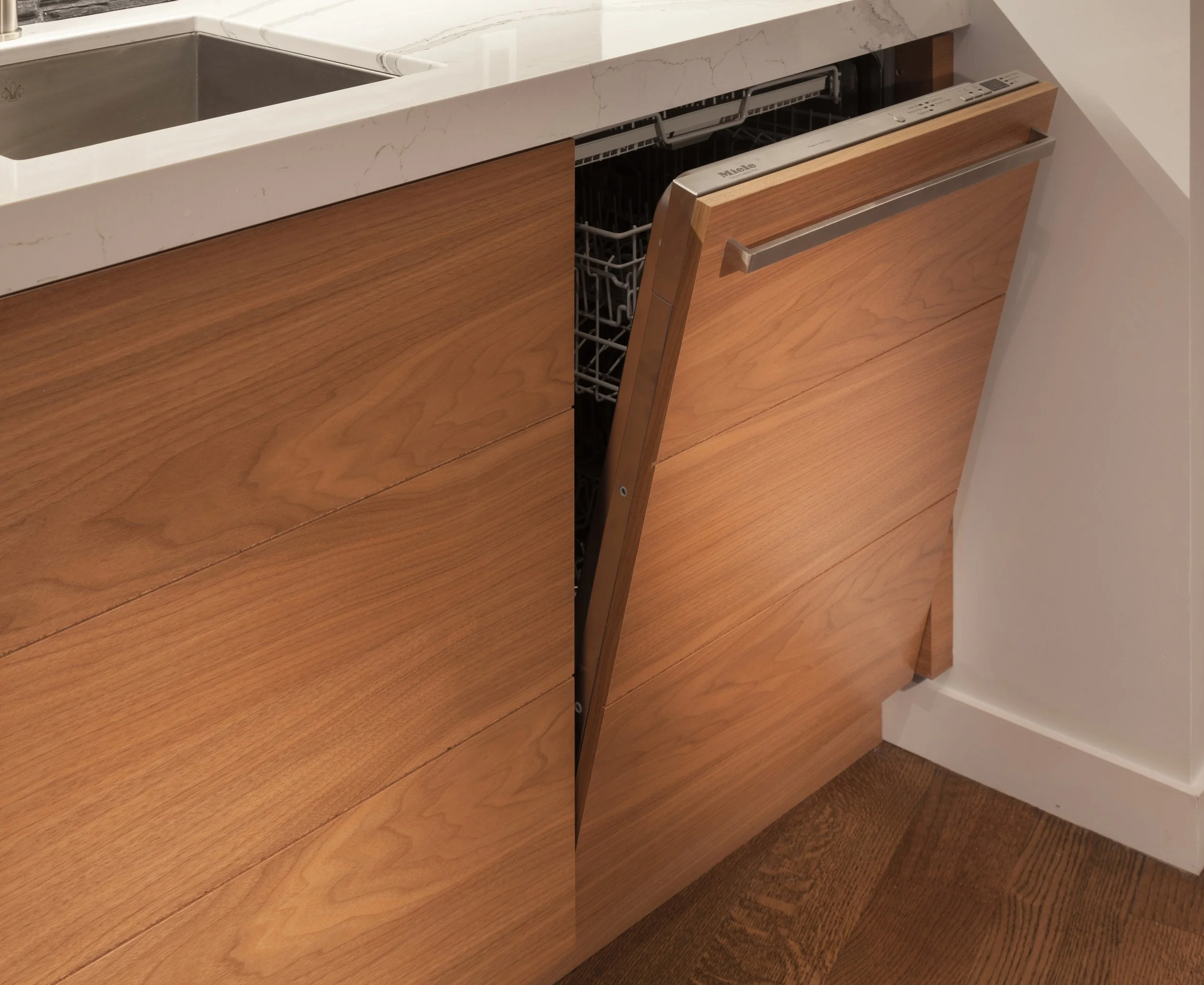 Kitchen cabinet with a built-in dishwasher, wooden panel, and a white marble countertop