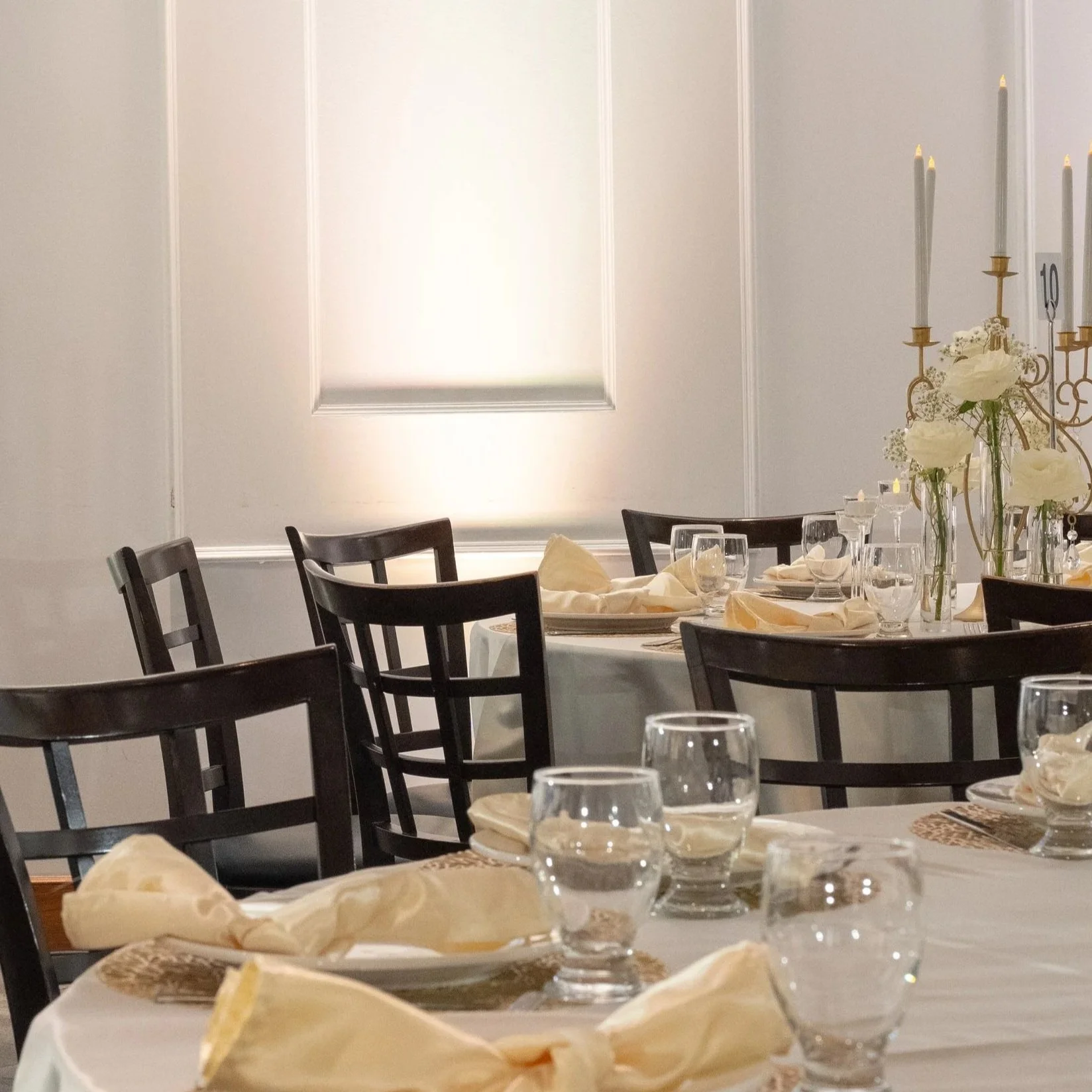 Elegant dining table set with napkins, glasses, and floral centerpiece in a formal room.