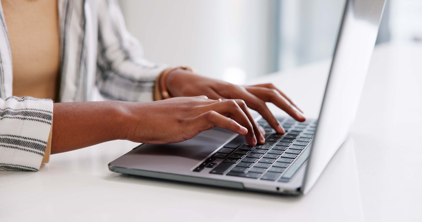 Person typing on a laptop keyboard at a desk.
