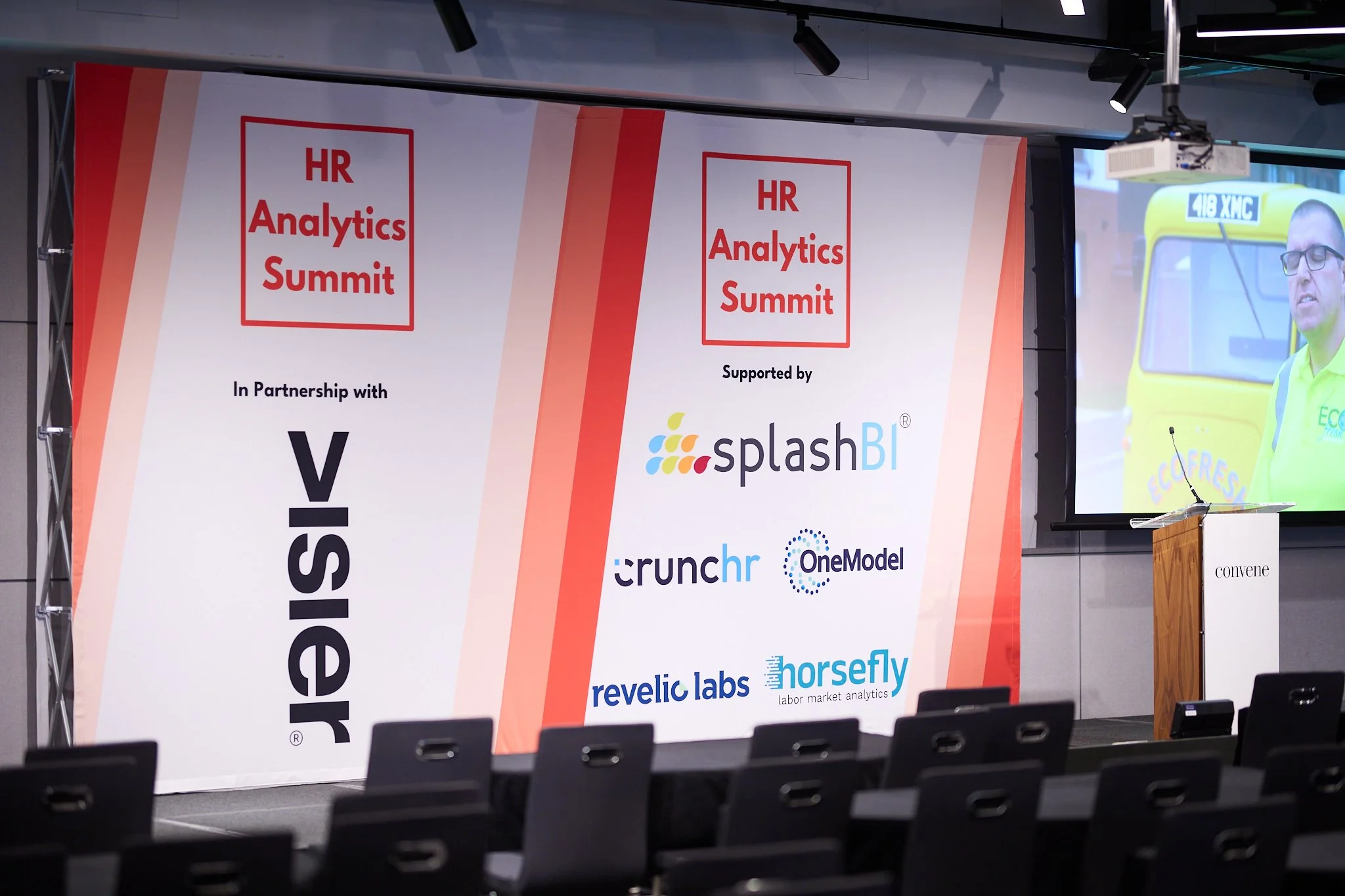 Stage setup at HR Analytics Summit with logos of partner and supporting companies including Visier, splashBI, Crunchr, OneModel, Revelic Labs, and Horsefly. Empty chairs and a podium with 'convene' branding are visible.