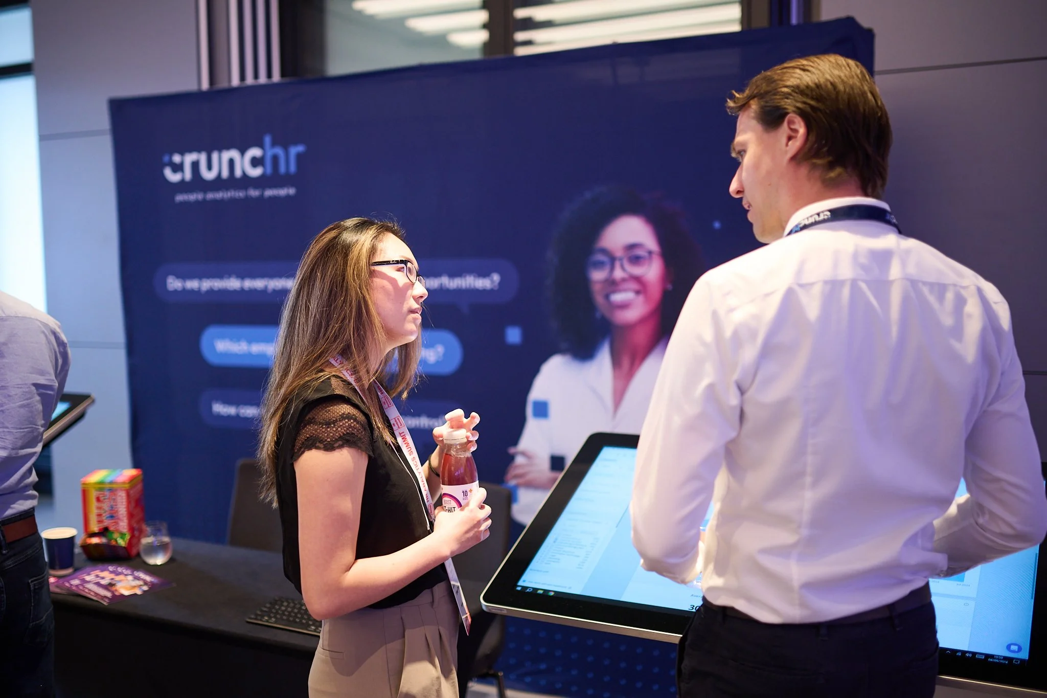 Two people engaged in conversation at a tech conference booth, with a 'crunchr' banner in the background.