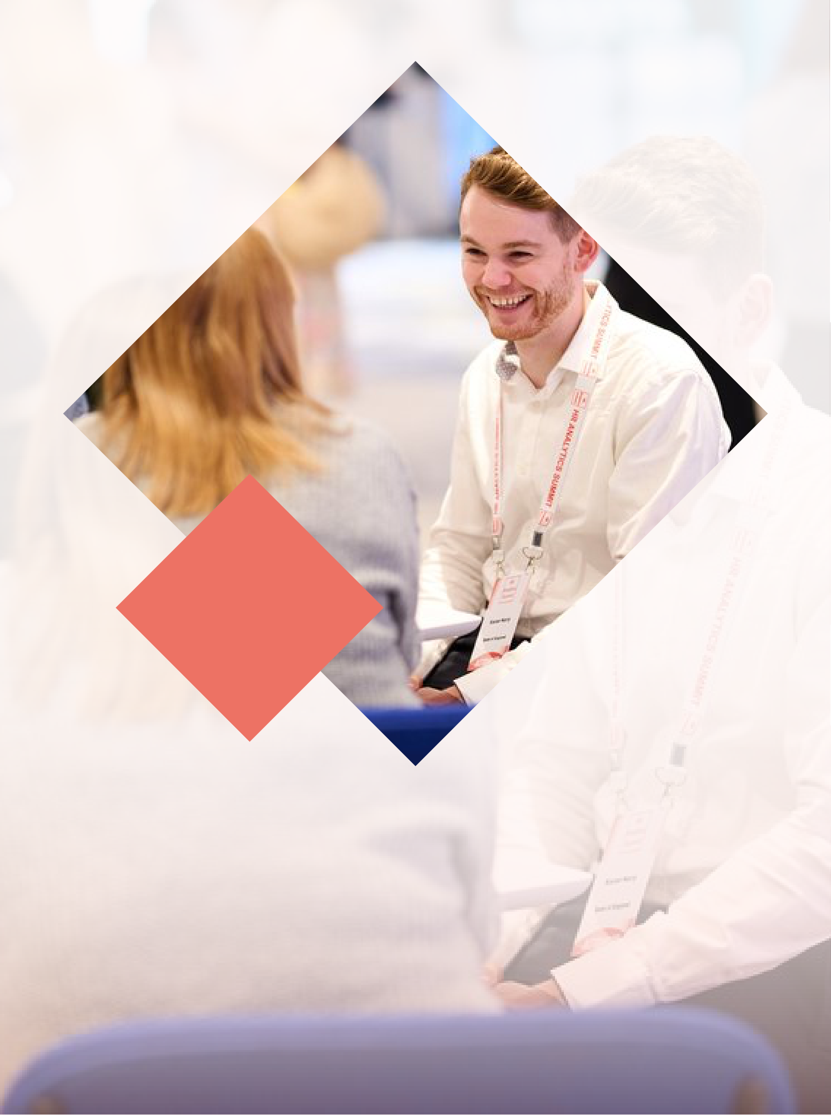 Two people talking at a professional event, one facing the camera, wearing a lanyard and smiling.