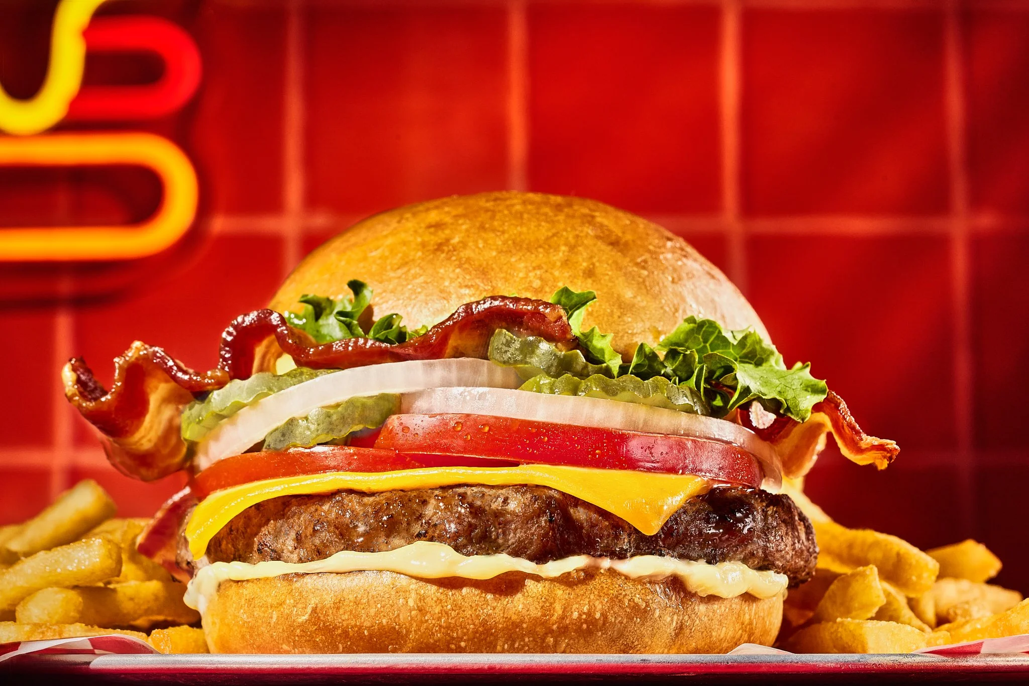 Bacon cheeseburger with lettuce, tomato, onion, and pickles styled with French fries by a Denver food stylist—one of the best food stylists in Colorado