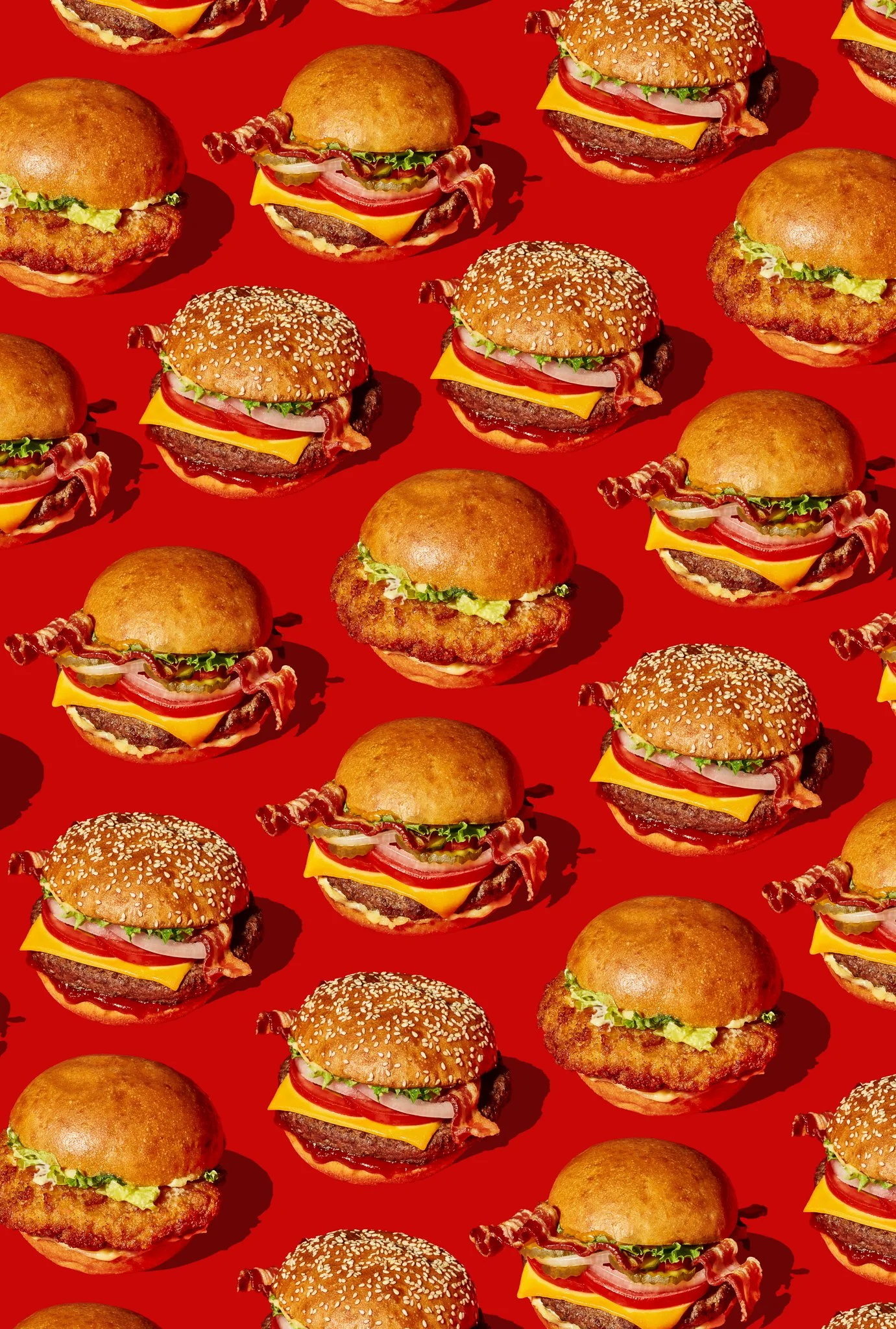Assorted burgers and chicken sandwiches on a red background. The professional food stylist is Chris Caldes, based in Denver, available nationally.