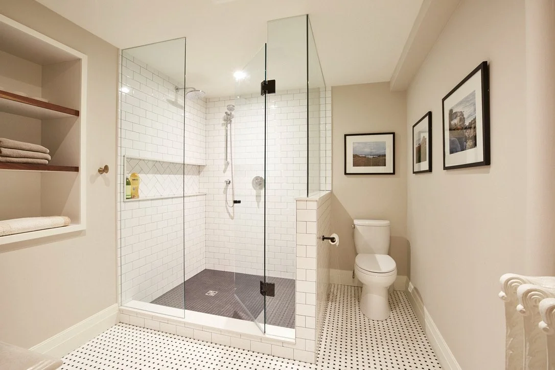 Basement bathroom with subway and penny tiles with a custom glass shower enclosure