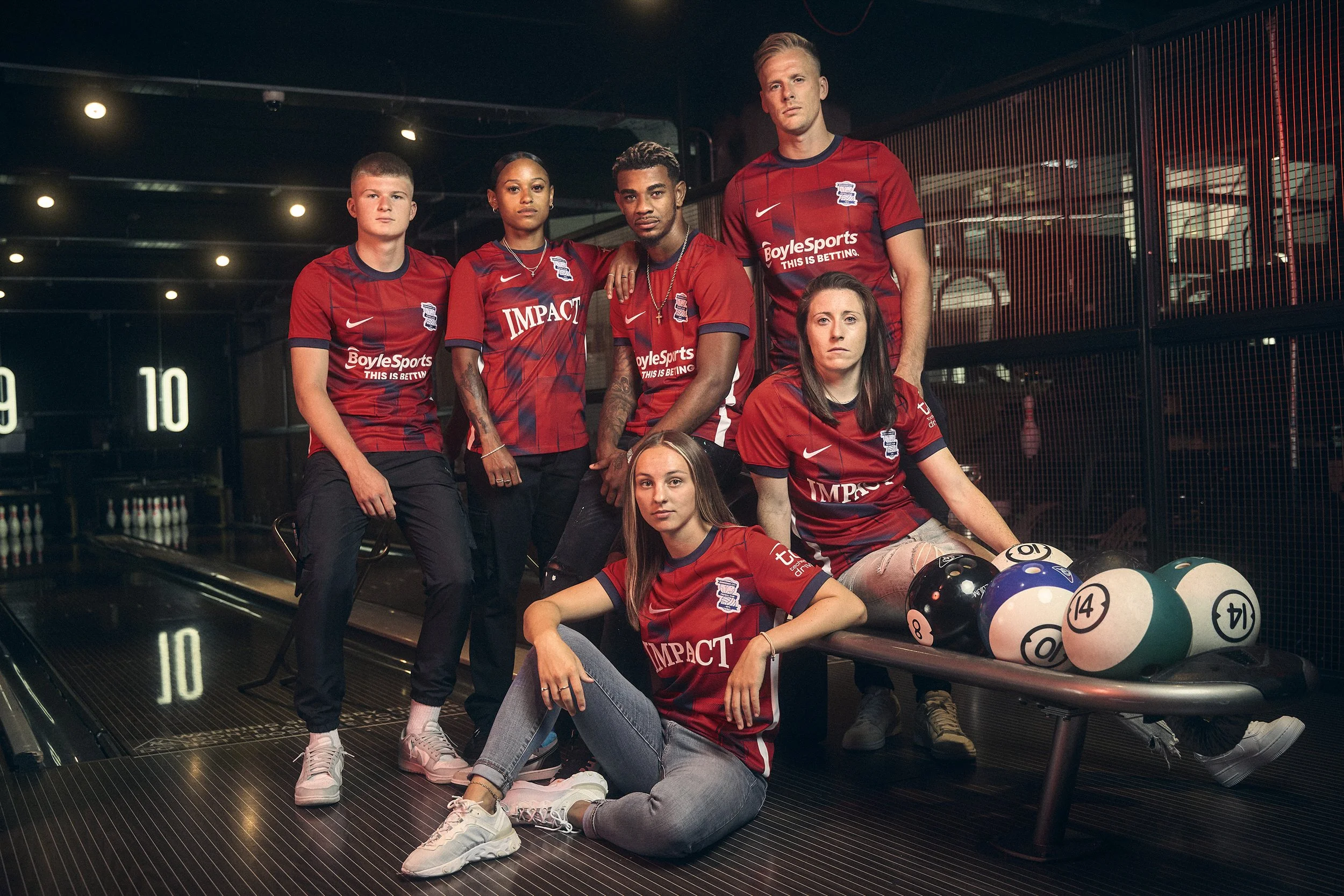 Football Players from Birmingham City FC posing in a bowling alley next to a rack of bowling balls.