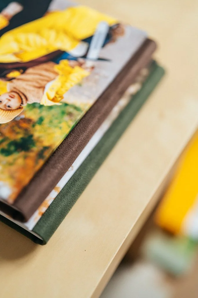 Stack of photo albums with colorful covers on a wooden surface