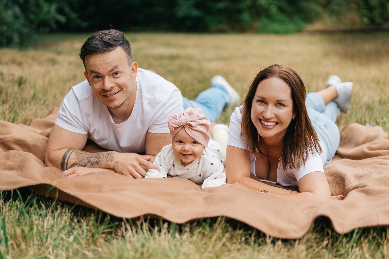 Nikola, Viktor a Sofie společně leží na dece v trávě a smějí se.