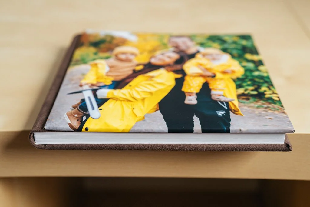 Photo book on a table with a custom cover image of a family wearing yellow jackets.