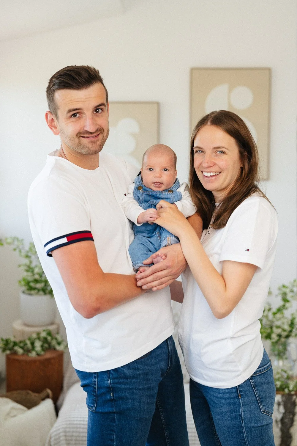 Usmívající se rodiče drží miminko mezi sebou.