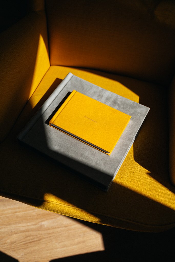 Yellow and gray books on a sunlit mustard chair