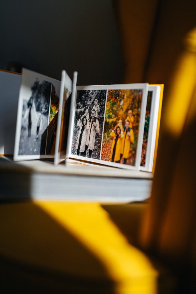 Photo album displaying family pictures on a yellow surface, with pages open to color and black-and-white images of people outdoors.