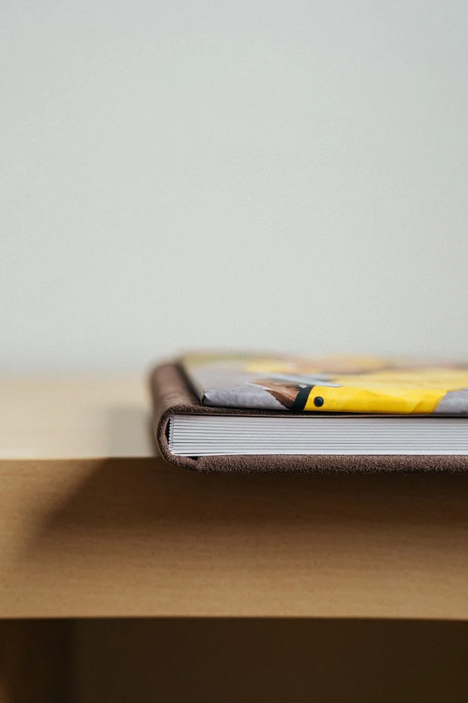 Edge of a closed hardcover book on a wooden table