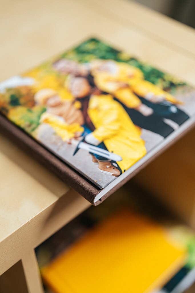 Photo album with colorful cover depicting blurred people in yellow clothing on a wooden table.