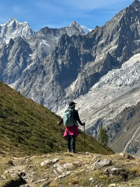 hiker on edge of vista viewing peaks of the alps while on the tour du mont blanc trail
