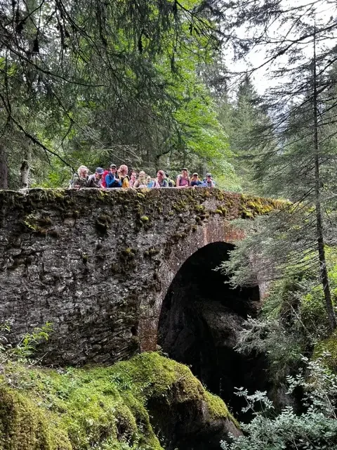 group of women hikers on old, moss covered bridge on the tour du mont blanc trail