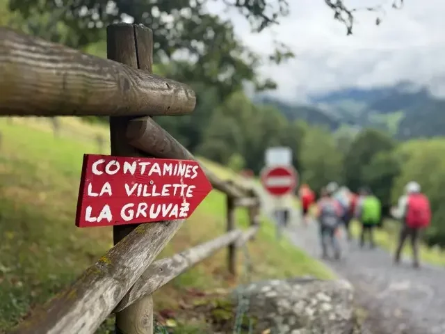 trail sign on a fence with blurry hikers in background
