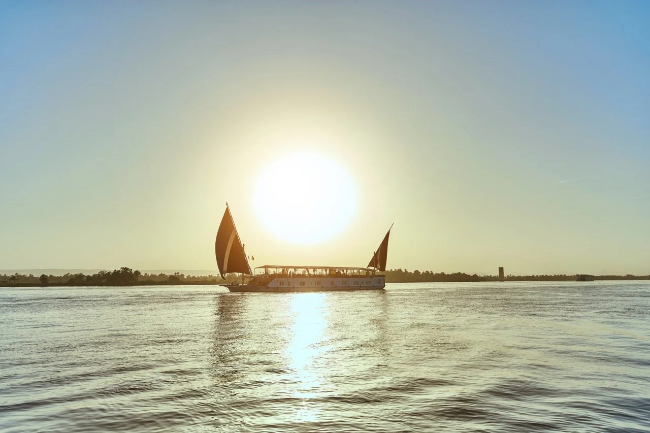 A boat sailing on a calm body of water during sunset