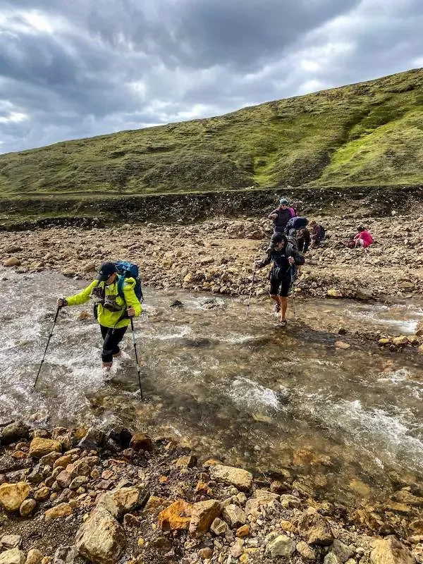 hikers crossing a small river in iceland on laugavegur trek