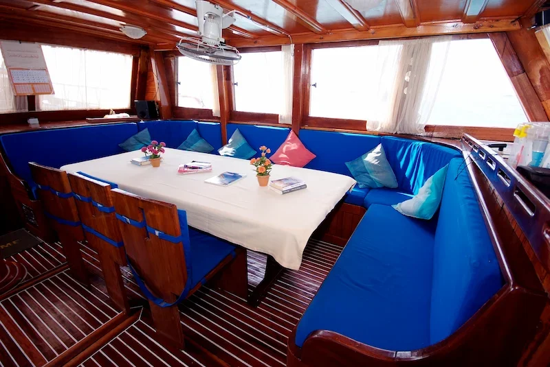 dining area on a sailboat wtih blue cushions and white tablecloth