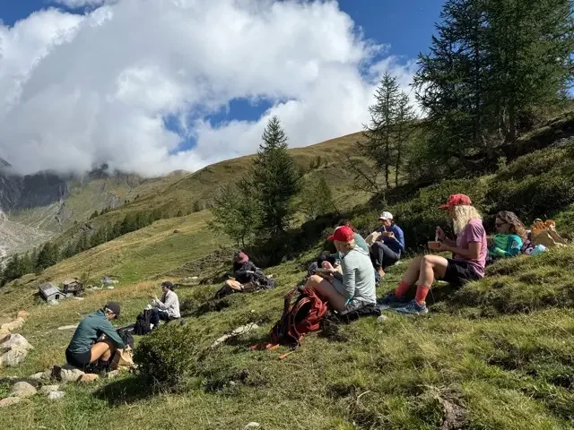 hikers resting on a green field overlooking a valley