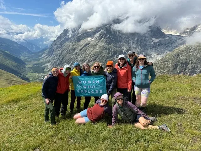 group of women hikers in field on the tour du mont blanc with the alps in background