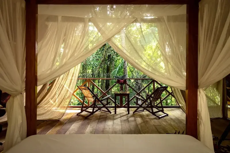 two wood chairs on patio overlooking jungle from bedroom