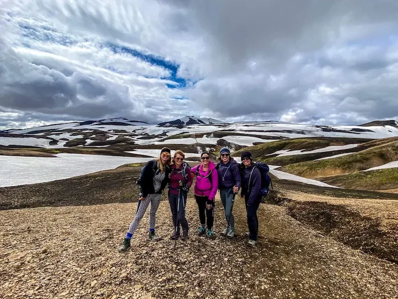 group of women hikers on laugavegur trek with snowy patches and clouds in background