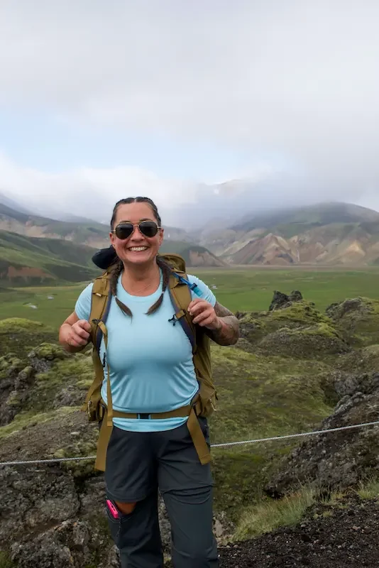 smiling woman hiker in front of green field on laugavegur trek in iceland