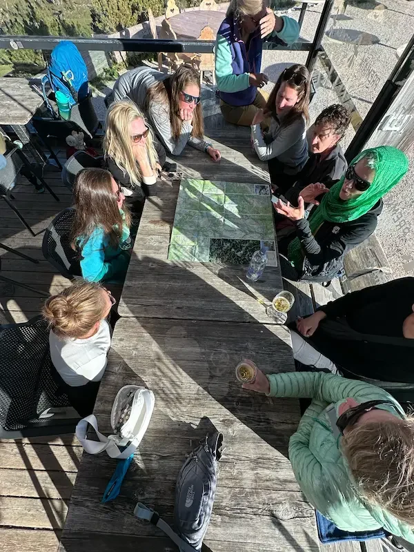 group of women at table studying dolomites trail map
