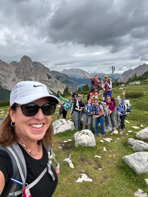 selfie of group of women hikers in dolomites with mountains a low clouds