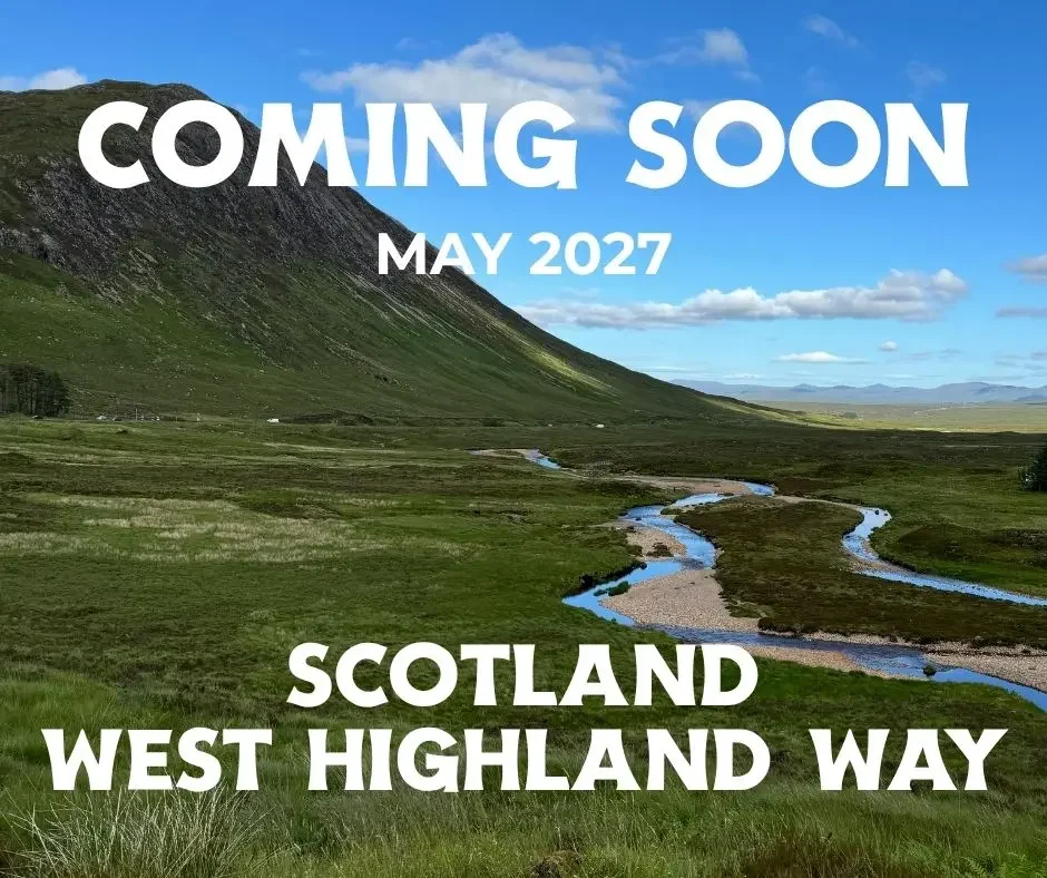scottish highlands with green hills and stream with blue sky