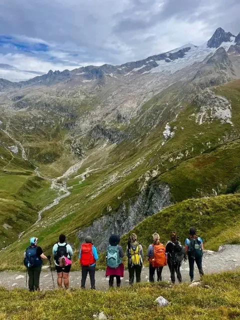 group of hikers overlooking winding valley on tour du mont blanc trail