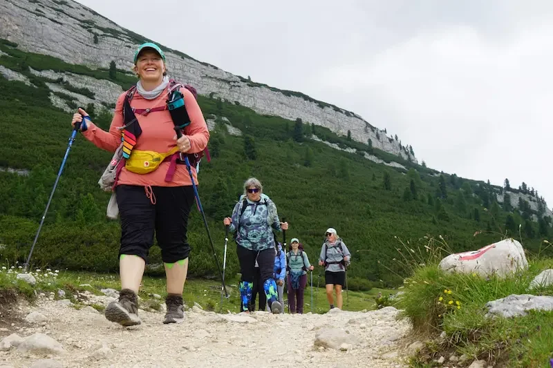 women hiking up a trail in the mountains wtih green grass