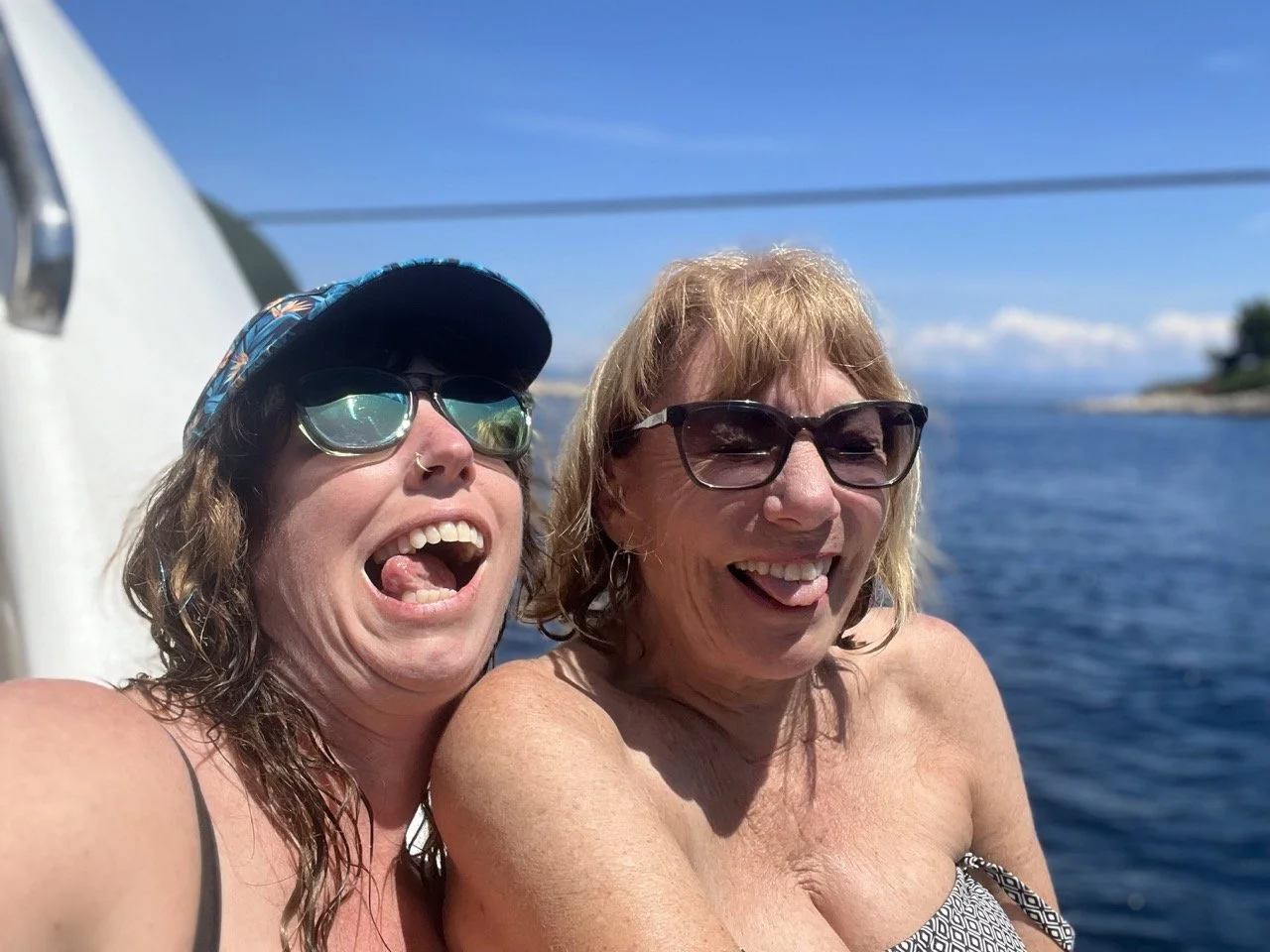 mom and daughter making faces on a boat with ocean in background