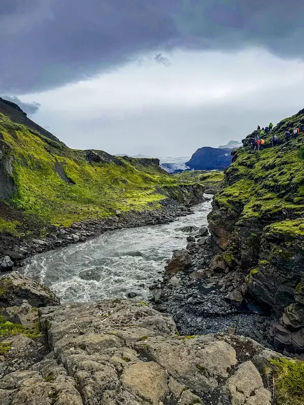 hikers walking along a small valley with river at bottom of laugavegur trek