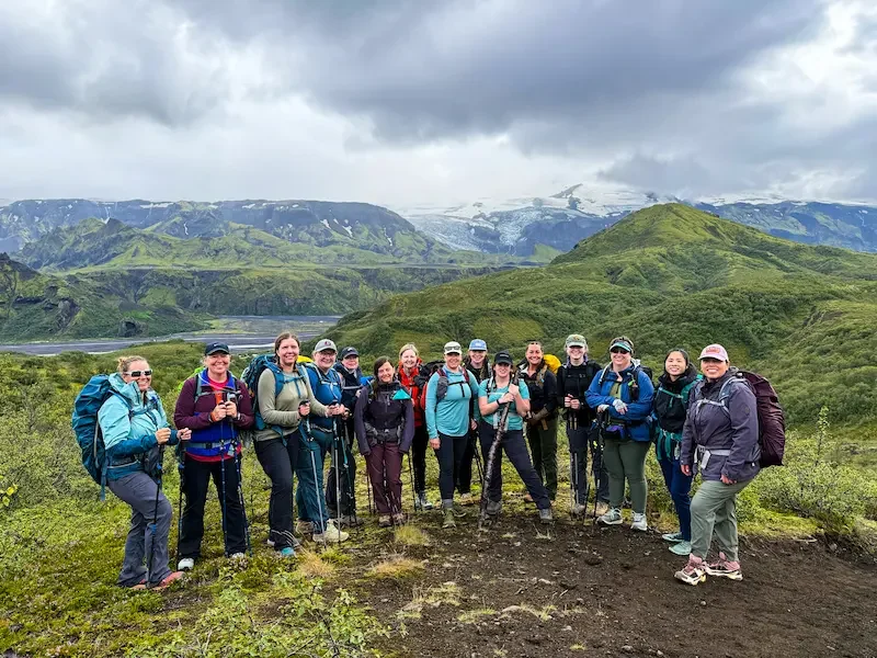 group of women hikers in front of grassy green mountains in iceland