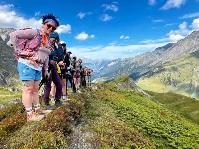 group of hikers on tour du mont blanc trail with alps in the distance