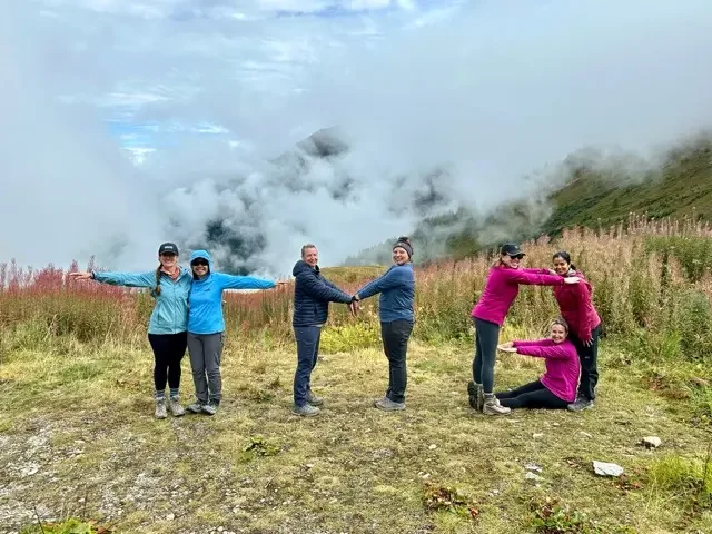 women hikers forming a T M B with their bodies since they are hiking the tour du mont blanc
