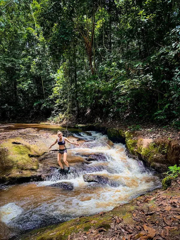 woman walking down small waterfall feature in amazon rainforest