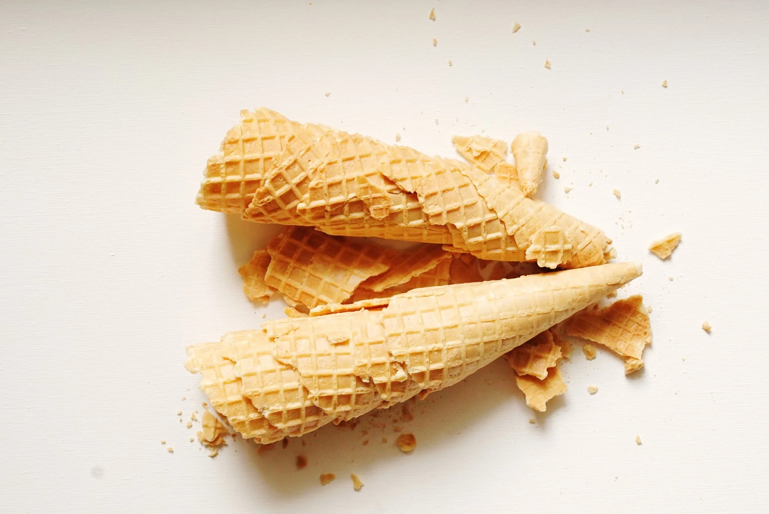 Broken ice cream cones on a white surface.