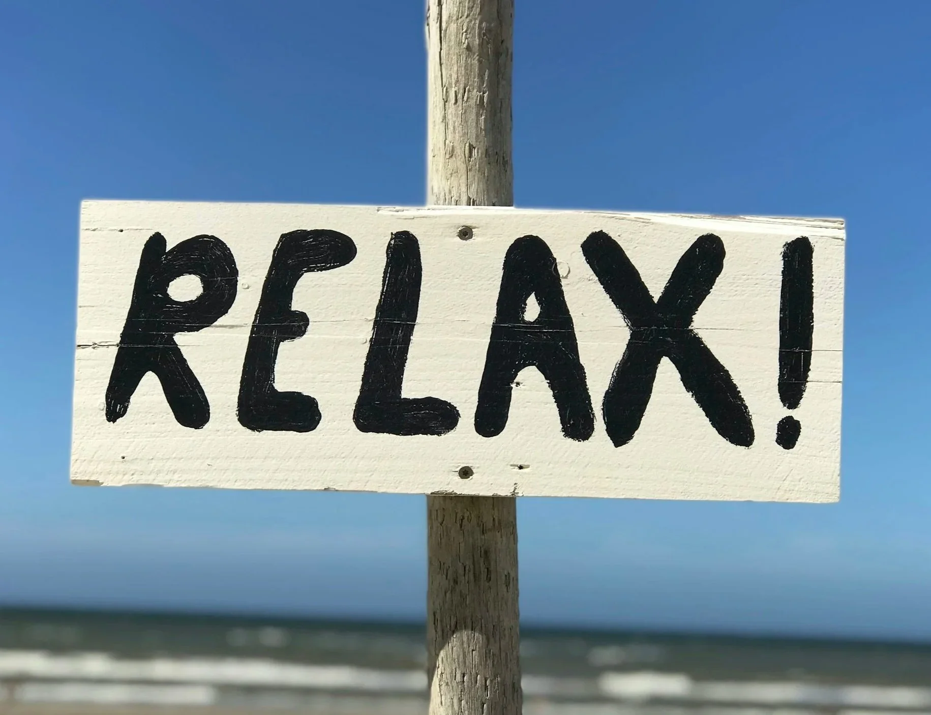 Schild mit der Aufschrift 'Relax!' vor blauem Himmel.