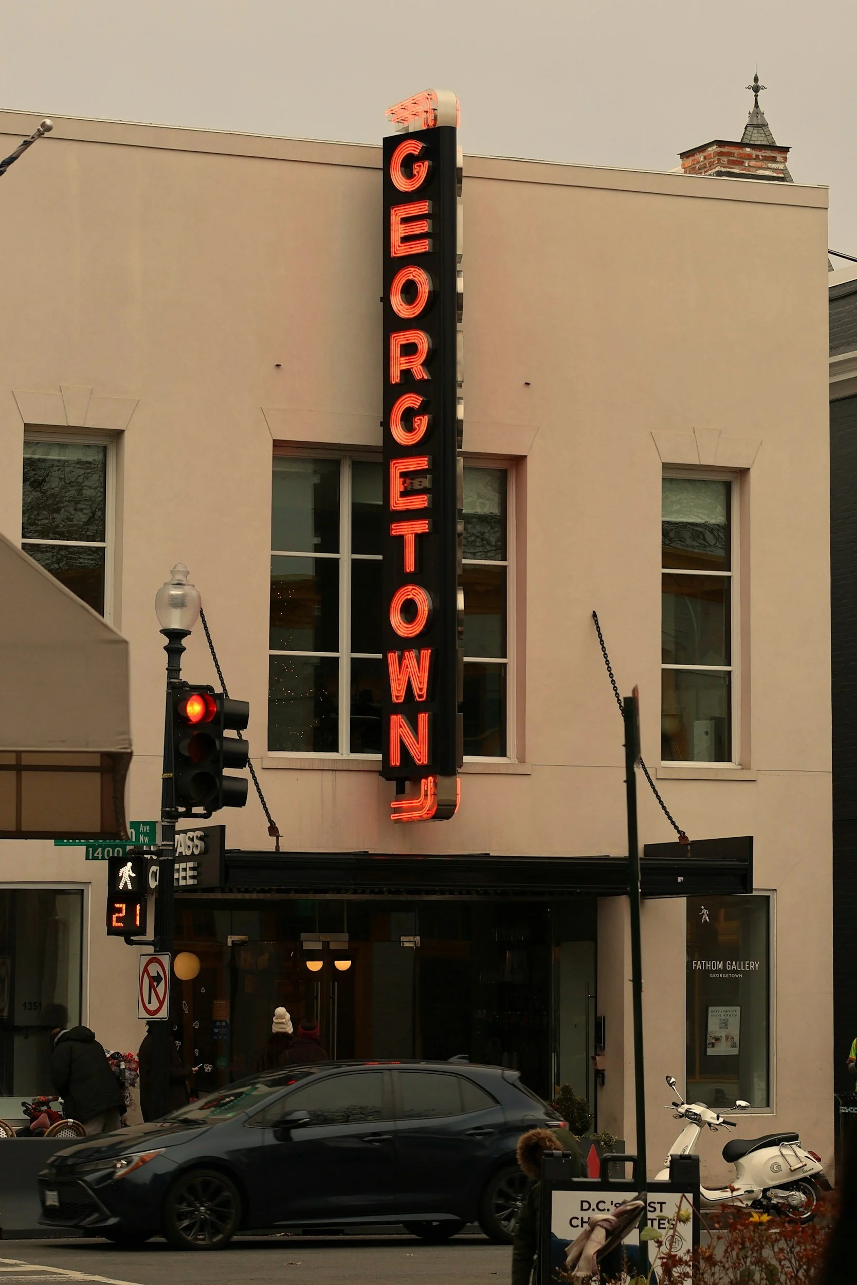 A vertical neon sign reading 'GEORGETOWN' in red letters on a building facade in Washington, D.C.