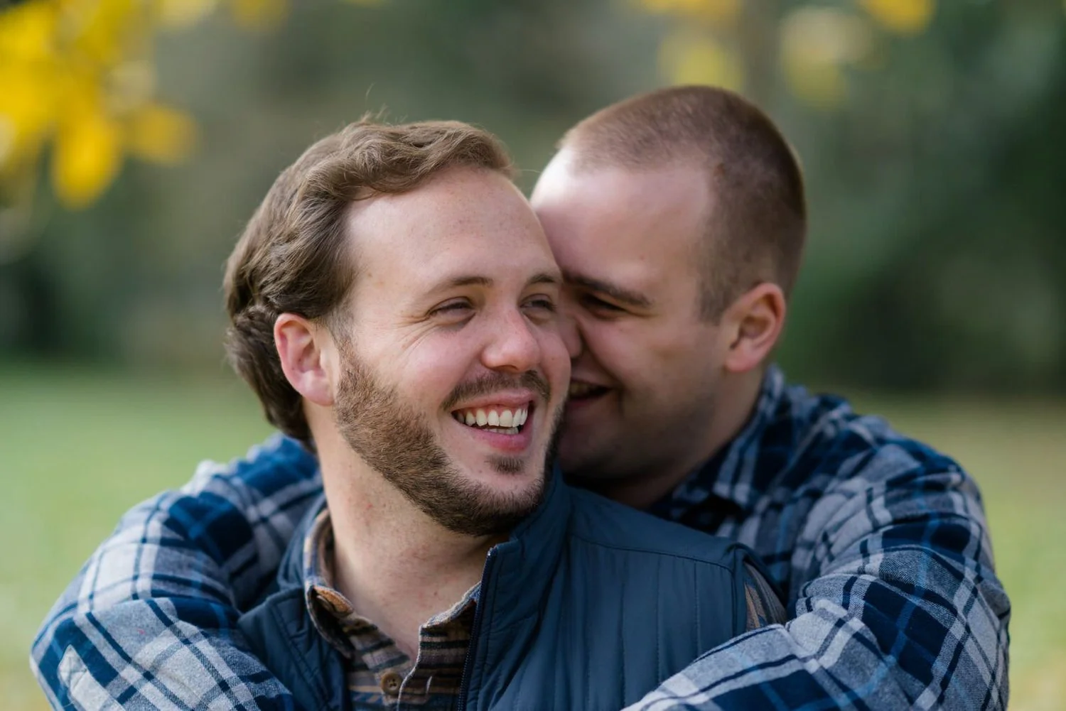 Gay engagement photos in Oregon forest with fall leaves and romantic moments.