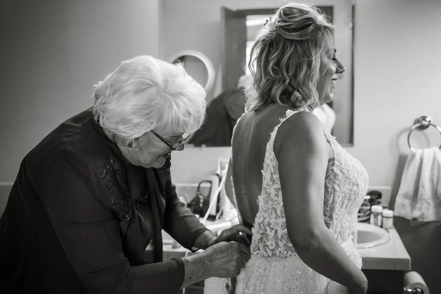 Grandmother helping bride zip wedding dress during intimate getting ready moment at family home backyard wedding in Vancouver Washington.