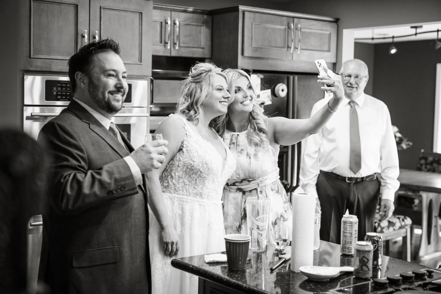 Bride and groom taking selfie with family during getting ready celebration inside family home before backyard wedding in Vancouver WA.