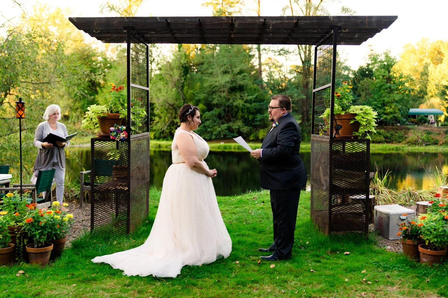 Backyard elopement in Clackamas, Oregon featuring a couple standing beneath a garden pergola during an intimate ceremony.
